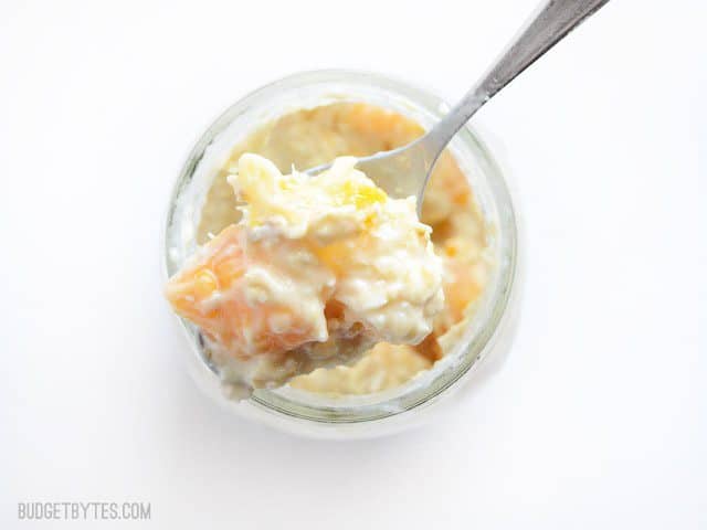 Tropical Yogurt Parfaits are the perfect healthy summer breakfast when you're short on time. Prepare them on the weekend and eat good all week. Budetbytes.com Close up of a spoonful of the stirred tropical yogurt overnight oat parfait