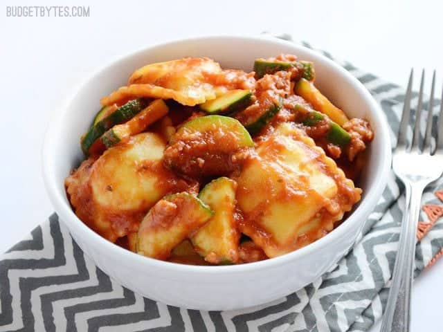 Adding a healthy dose of vegetables to these grocery store staples makes this Zucchini Sausage Ravioli a quick, delicious, and healthy weeknight dinner. Budetbytes.com Side view of a bowl of Zucchini Sausage Ravioli on a zig zag napkin