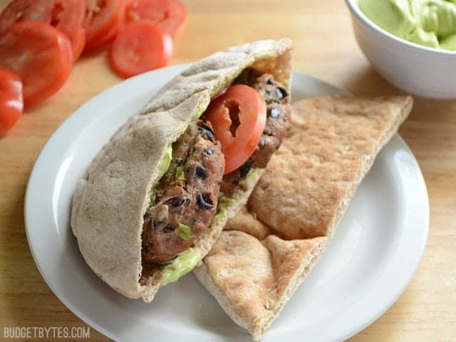 These flavorful mini black bean turkey burgers come together quickly and bake in the oven for a fast, no fuss dinner. Step by step photos. Budetbytes.com Mini Black Bean Turkey Burgers stuffed into a pita with tomato and avocado sauce