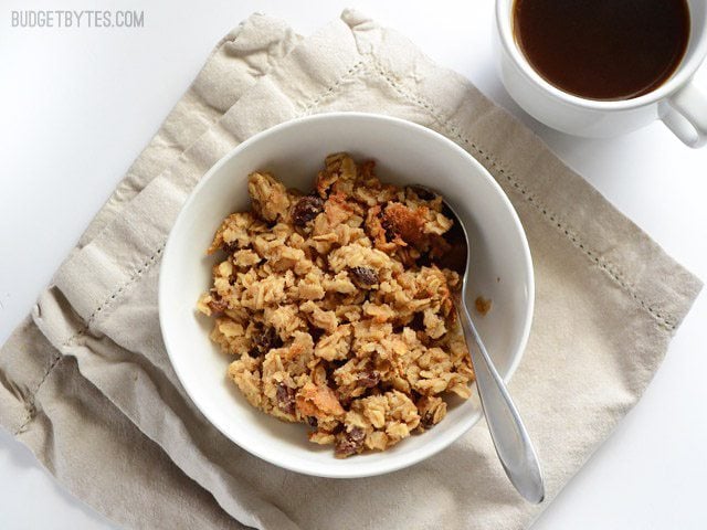 This freezable Oatmeal Cookie Baked Oatmeal tastes like an oatmeal cookie's older, more healthful sibling. Perfect for breakfast meal prep. Budetbytes.com A bowl of oatmeal cookie baked oatmeal on a napkin with a mug of coffee on the side