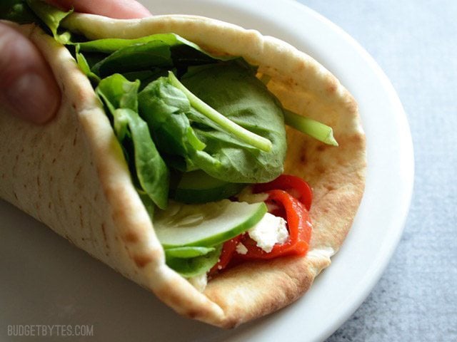 These quick and flavorful Roasted Red Pepper Hummus Wraps are a great no-cook, no-reheat lunch idea. A fresh and light lunch for summer! Budetbytes.com Close up of hummus wrap folded closed.