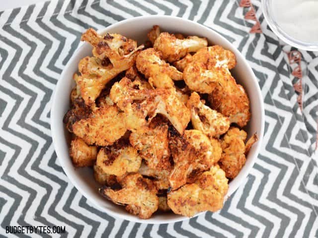 Smoky Parmesan Roasted Cauliflower is an easy, smoky, and savory side dish or snack for dipping in your favorite sauces. Step by step photos. Budetbytes.com Overhead view of a bowl of Smoky Parmesan Roasted Cauliflower on a zig zag napkin
