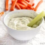 A bowl of dilly vegetable dip served with celery sticks.