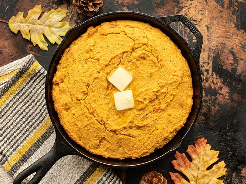 Mashed sweet potato, fragrant spices, and rich sour cream make this Sweet Potato Cornbread a decadent fall treat. Budgetbytes.com baked sweet potato cornbread with butter on top