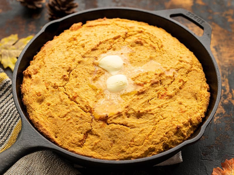 Mashed sweet potato, fragrant spices, and rich sour cream make this Sweet Potato Cornbread a decadent fall treat. Budgetbytes.com Front view of sweet potato cornbread in the skillet with butter melting on top
