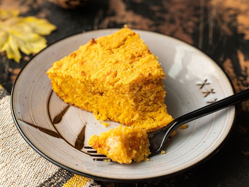 Mashed sweet potato, fragrant spices, and rich sour cream make this Sweet Potato Cornbread a decadent fall treat. Budgetbytes.com One slice of sweet potato cornbread on a plate with a fork