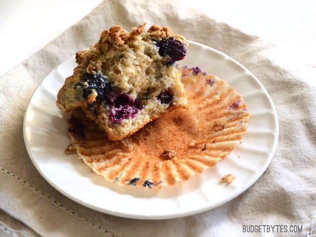 These big, moist, and fluffy Triple Berry Oatmeal Muffins are a real treat for breakfast and boast the goodness of rolled oats. Freezer friendly! Budetbytes.com A half eaten Triple Berry Oatmeal Muffin on a plate
