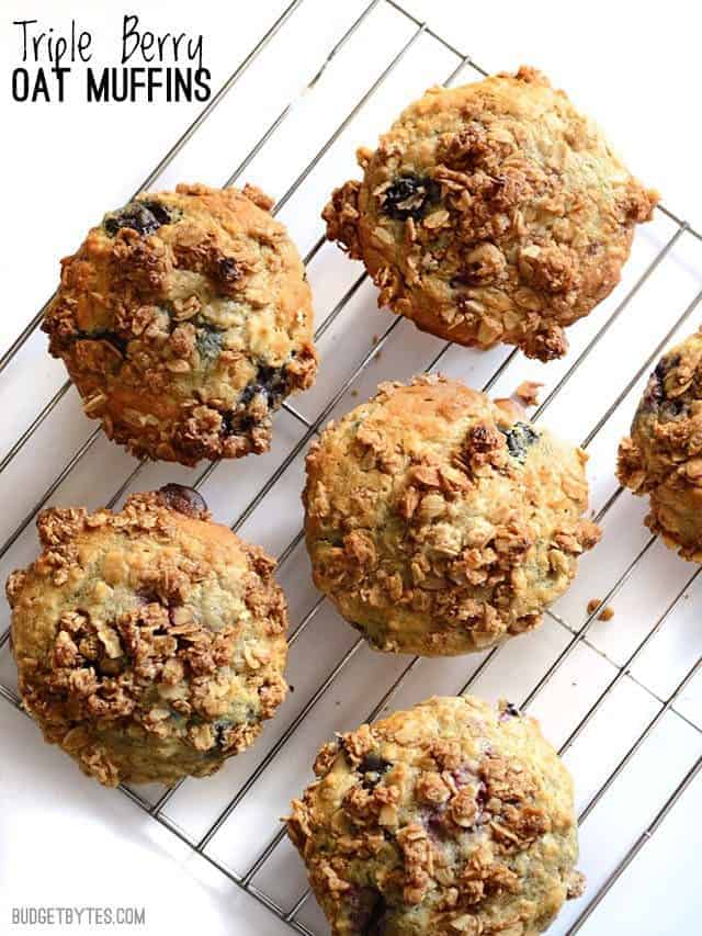 These big, moist, and fluffy Triple Berry Oatmeal Muffins are a real treat for breakfast and boast the goodness of rolled oats. Freezer friendly! Budetbytes.com Overhead view of Oatmeal Muffins on the wire cooling rack