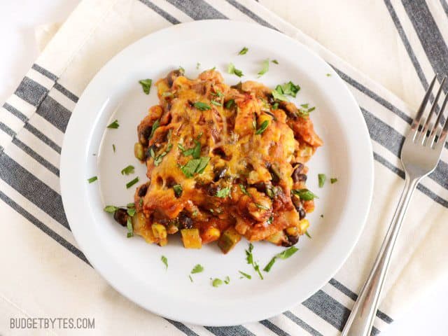 A colorful mix of vegetables, homemade enchilada sauce, corn tortillas, and cheese make this Vegetable Enchilada Casserole an ultimate comfort food.. Budetbytes.com Overhead view of one serving of Vegetable Enchilada Casserole on a plate