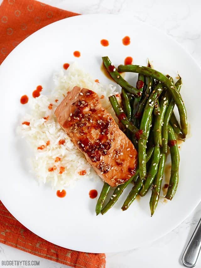 This incredible fast and easy Sesame Glazed Salmon dinner is faster than take-out and fancy enough to impress your friends and family. Budetbytes.com Sesame Glazed Salmon and Green Beans plated with jasmine rice and sriracha