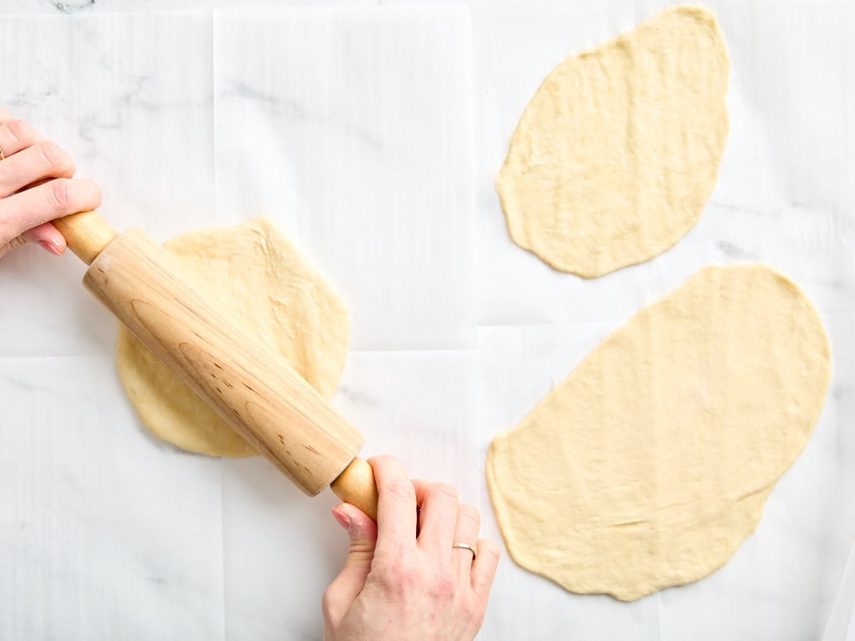 A rolling pin flattening naan dough.