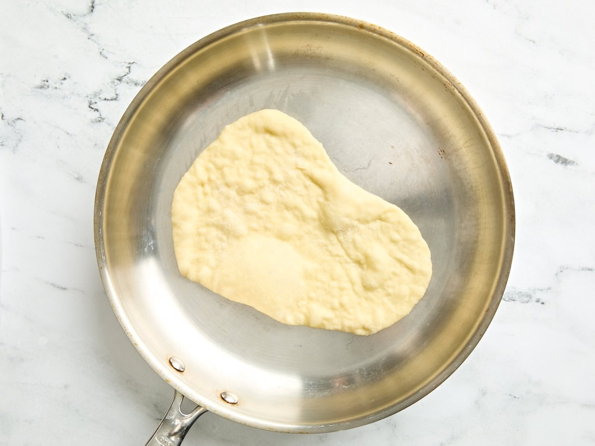 A naan cooking in a skillet.