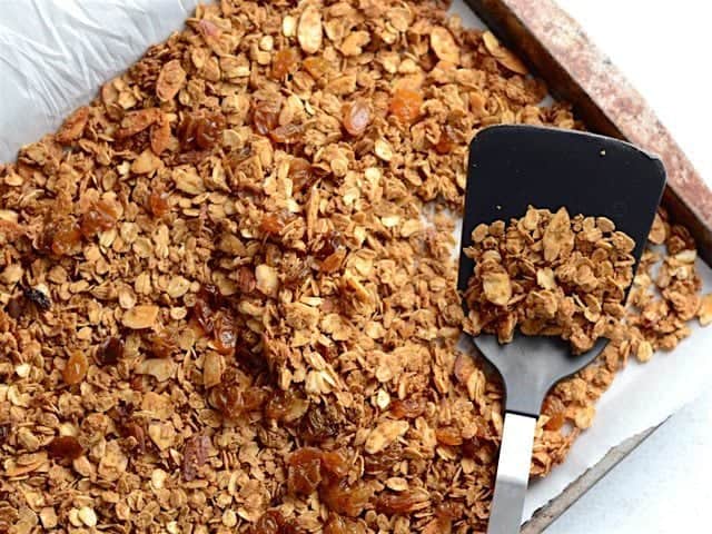 Gingersnap Granola pairs the rich, deep flavor of molasses with warm spices like ginger, cinnamon, and cloves. Great for breakfast, a snack, or dessert! Budetbytes.com Finished gingersnap granola on the baking sheet with a spatula