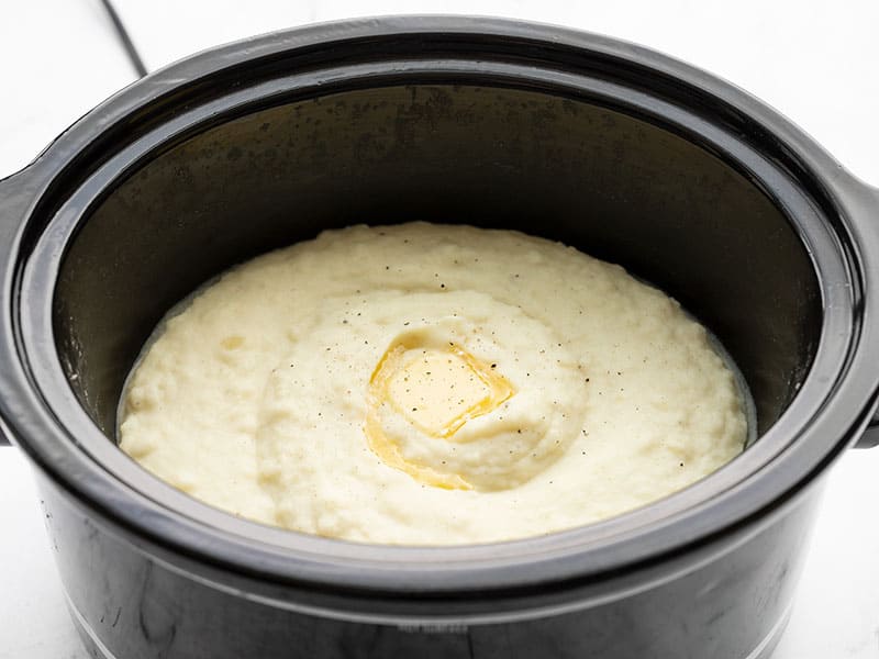 Slow cooker mashed potatoes are the perfect hands-off method for making rich and creamy mashed potatoes for the Holidays! Budgetbytes.com Side view of mashed potatoes in the slow cooker with melted butter