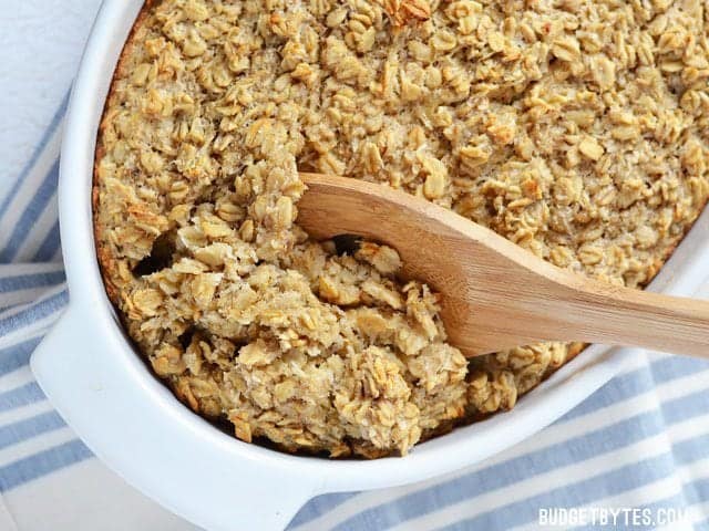 Rich and slightly sweet, this Banana Coconut Baked Oatmeal tastes indulgent, but is a balanced, fiber filled breakfast that will keep you full all morning! Budetbytes.com Banana Coconut Baked Oatmeal in a casserole dish being scooped out with a wooden spoon