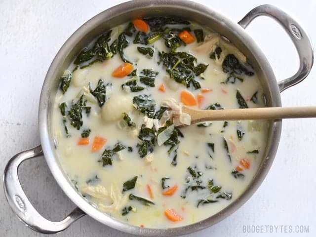 Take your classic chicken soup up a notch with the addition of kale, gnocchi, and cream. Creamy Chicken Gnocchi Soup with Kale is a warm and comforting meal! Budetbytes.com Finished chicken gnocchi soup with kale in the soup pot, a wooden spoon in the center