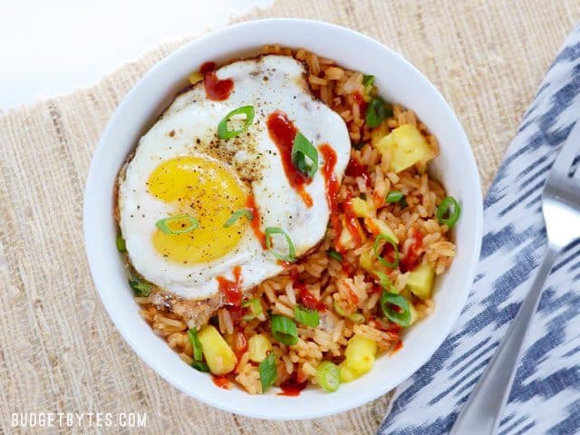 Use up the leftovers in your fridge with these fast and tasty Pineapple Sriracha Breakfast Bowls. Easy and customizable to fit what you have on hand. Budetbytes.com Overhead view of a Pineapple Sriracha Breakfast Bowl on a natural fiber napkin