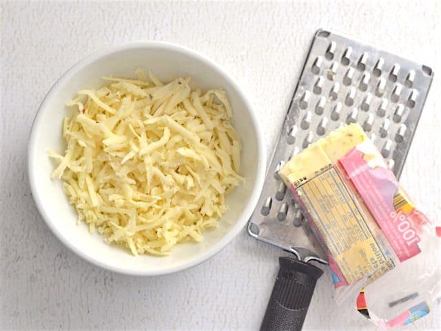 Cheese being shredded into a bowl