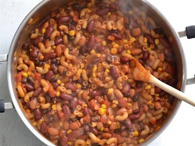 This rich and comforting One Pot Vegetarian Chili Mac and Cheese is the perfect quick and easy weeknight meal. Works great for meal prep! Budetbytes.com Simmered Chili Mac in the pot overhead view, wooden spoon in the pot