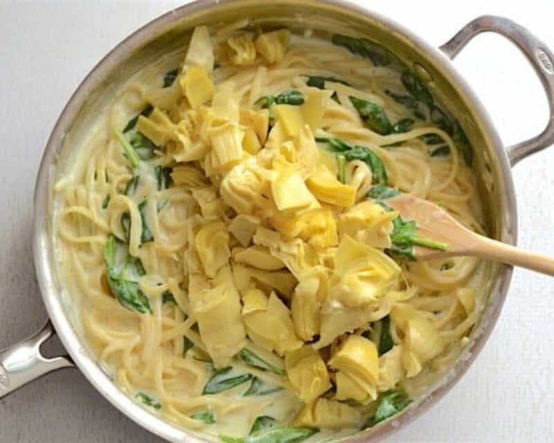 Adding artichokes to the pot.