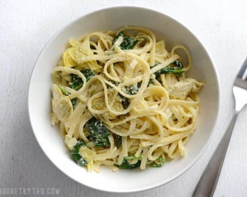 Creamy Spinach Artichoke Pasta is an easy one-pot weeknight dinner made with pantry staples, perfect for Meatless Monday! Budetbytes.com Overhead view of a bowl full of one pot creamy spinach artichoke pasta.
