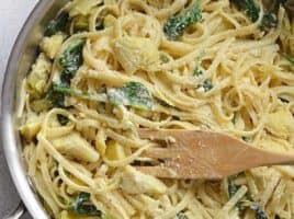 Creamy Spinach and Artichoke Pasta in a pot with a wooden spoon.
