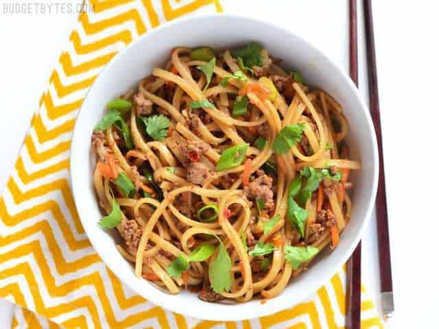 These everyday fast beef stir fry noodles are easy enough to make on a busy weeknight and delicious enough to keep you from calling for take-out. Budetbytes.com Beef Stir Fry Noodles served in a bowl on a yellow napkin, chopsticks on the side
