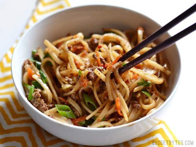 These everyday fast beef stir fry noodles are easy enough to make on a busy weeknight and delicious enough to keep you from calling for take-out. Budetbytes.com Beef Stir Fry Noodles in a bowl, chopsticks lifting a bite