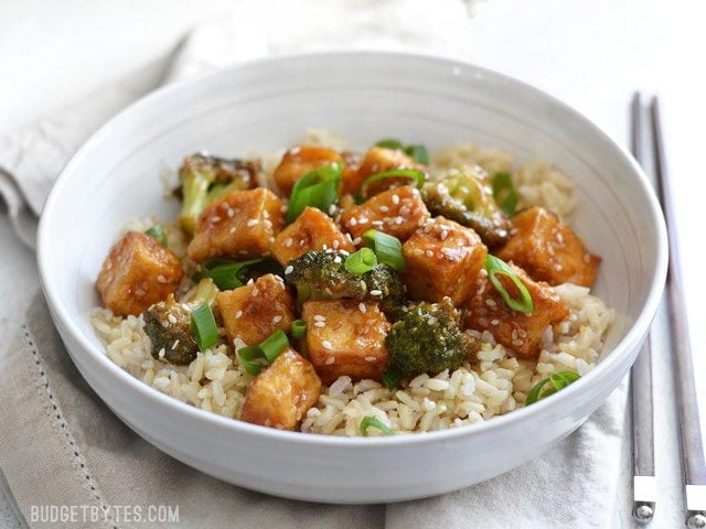 This Pan Fried Sesame Tofu is seriously crispy and drenched in a tangy sesame sauce. Broccoli florets and cooked rice make it a meal. Step by step photos. Budgetbytes.com Front view of Pan Fried Sesame Tofu with Broccoli and Brown Rice.