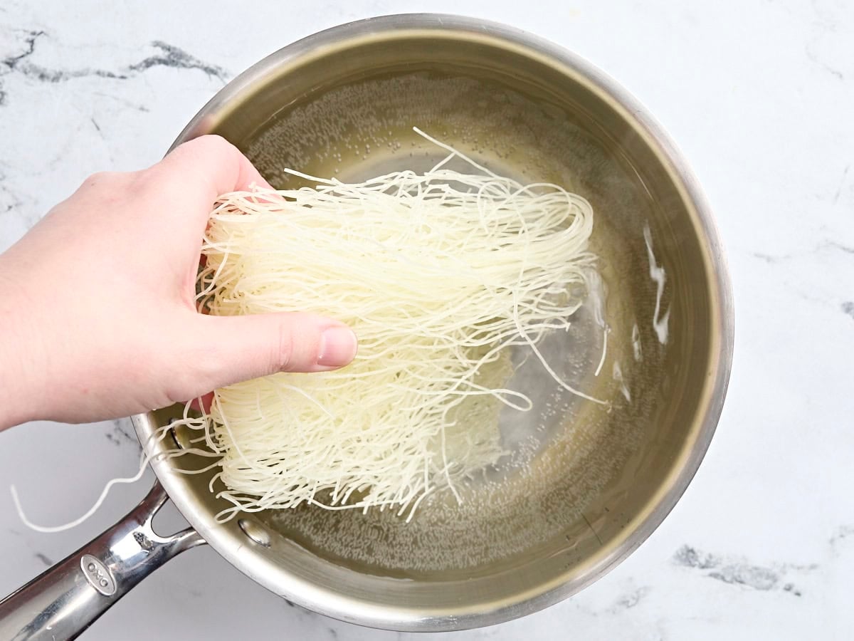 Noodles being added to a pot of water.