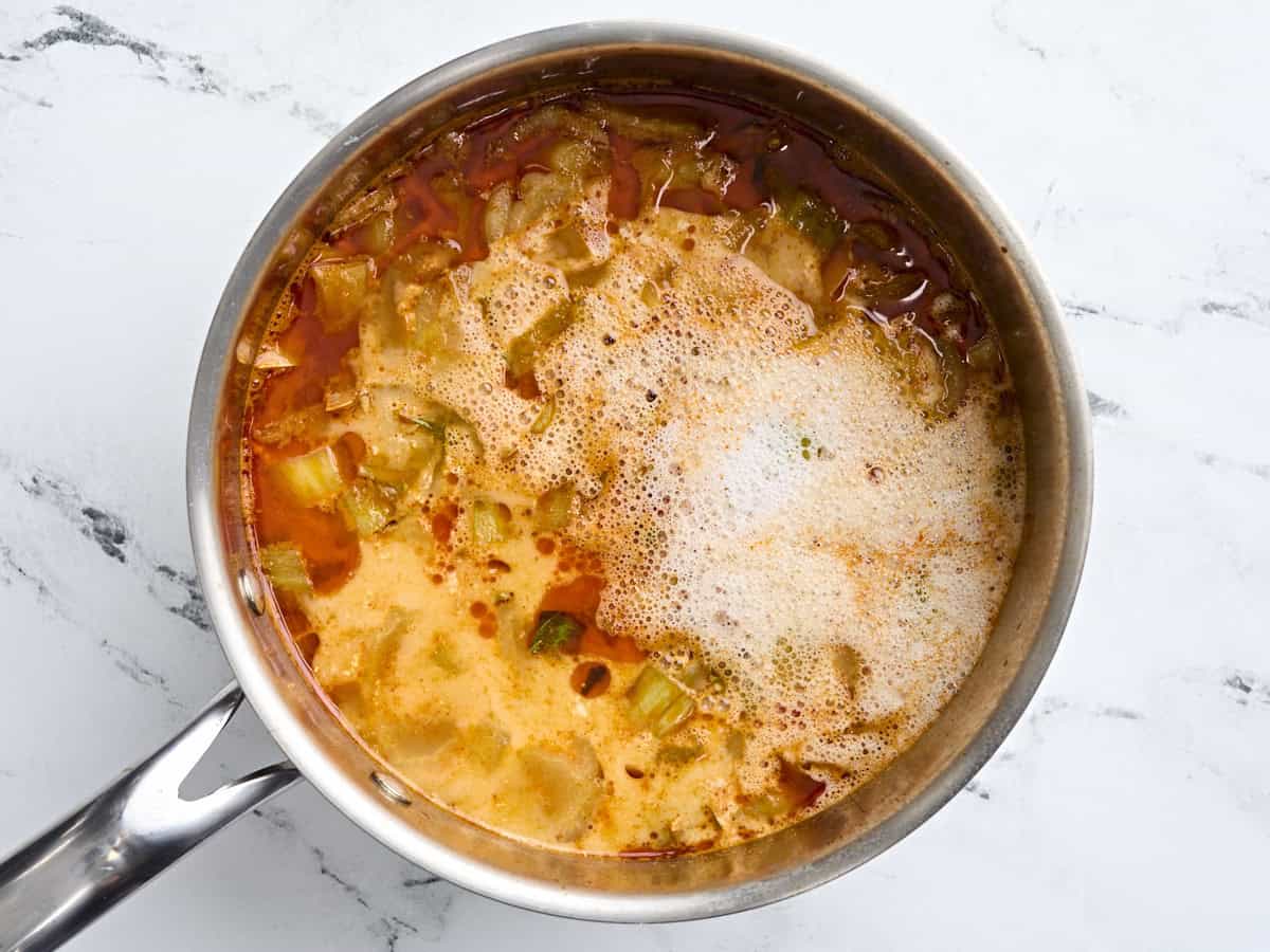 Coconut milk, fish sauce, and brown sugar added to a pot of thai curry vegetable soup.