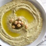 Close-up of creamy pesto hummus in a bowl.