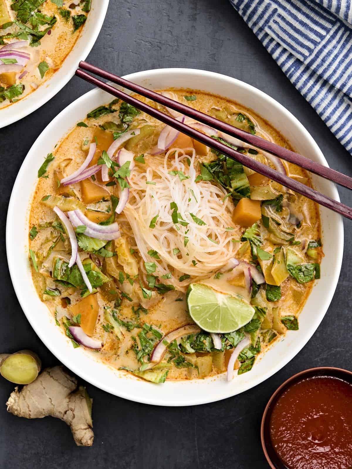 This Thai Curry Vegetable Soup is packed with vegetables, spicy Thai flavor, and creamy coconut milk. Ready in about 30 minutes! Step by step photos. Budgetbytes.com Overhead view of thai vegetable curry soup in a bowl with chopsticks.