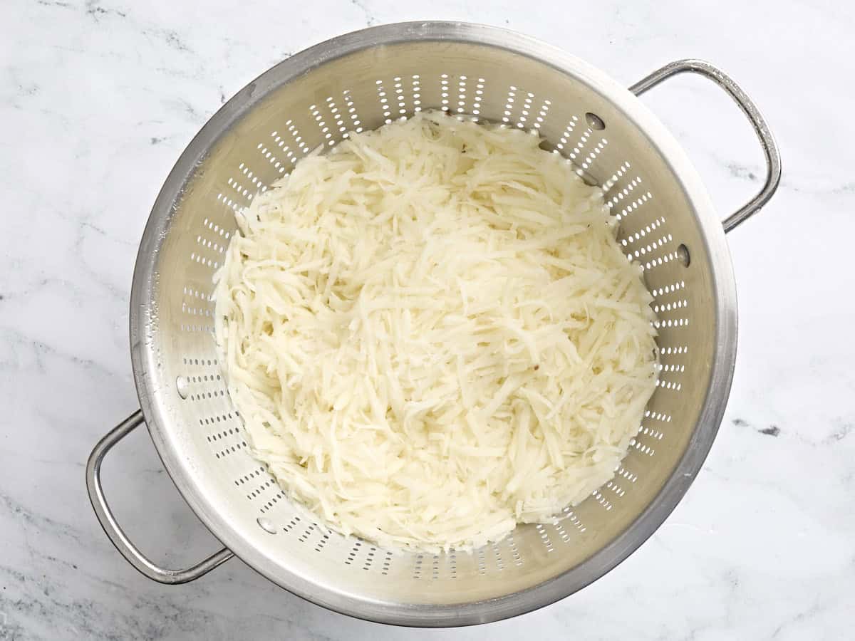 Shredded potatoes in a colander.