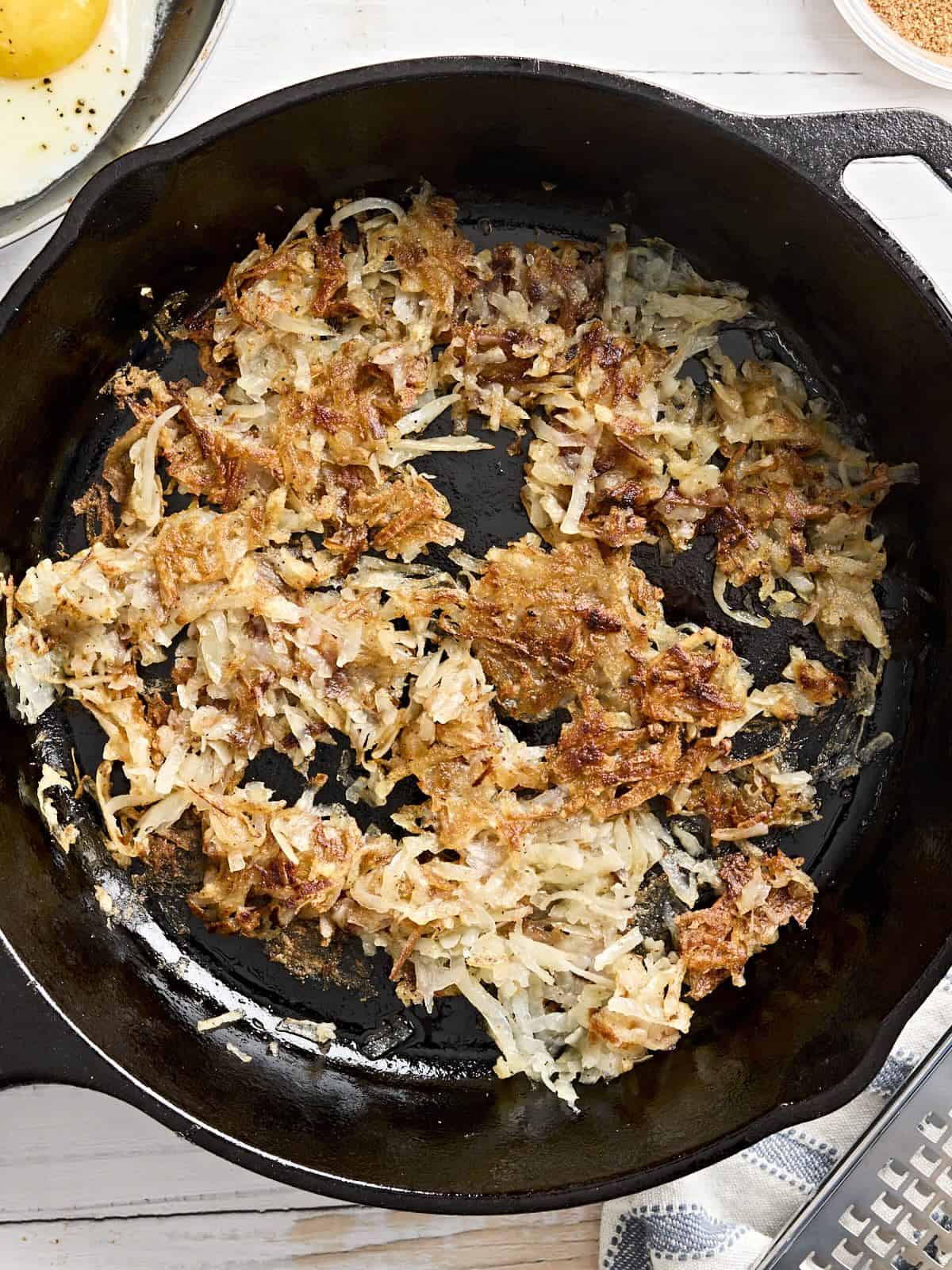 Overhead view of hashbrowns in a skillet.