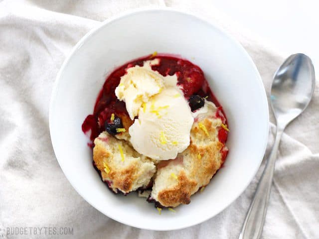 With the perfect mix of sweet and tart, this Lemon Berry Cobbler is the fastest and easiest way to sweet dessert satisfaction. Step by step photos. BudgetBytes.com Overhead view of a bowl of Lemon Berry Cobbler topped with vanilla ice cream