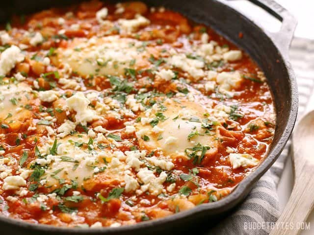 Eggs poached in a rich and smoky tomato sauce speckled with white beans, this Smoky White Bean Shakshuka is a filling and inexpensive breakfast or dinner! BudgetBytes.com Side view of a skillet full of Smoky White Bean Shakshuka