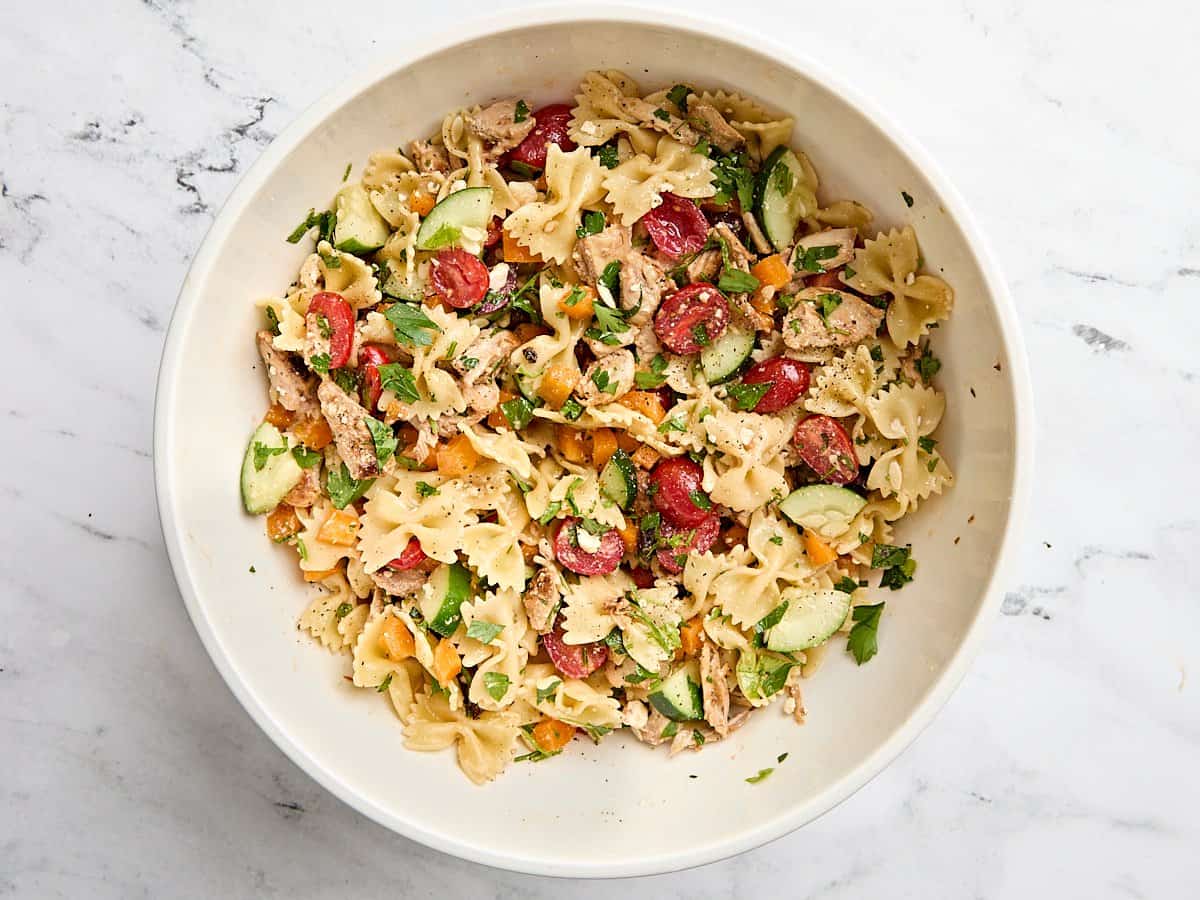 Greek Chicken Pasta Salad is the perfectly refreshing and filling summer meal with its medley of vegetables and tangy lemon garlic dressing. BudgetBytes.com Finished Greek chicken pasta salad in a mixing bowl.