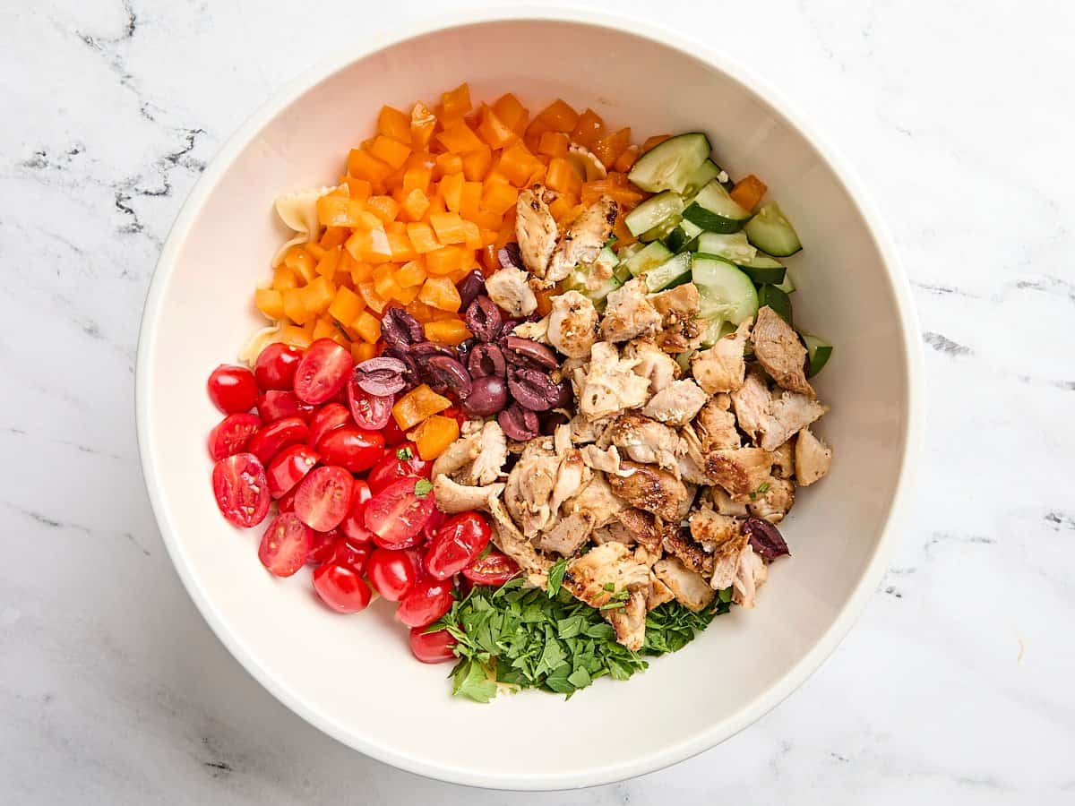 Diced chicken thighs and prepped salad veggies in a mixing bowl.