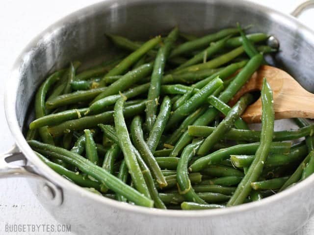 Lemon Butter Green Beans are an easy and flavorful way to cook fresh green beans, and a great all-purpose side dish for all your meals. BudgetBytes.com Side view of a skillet full of Lemon Butter Green Beans with a wooden spoon