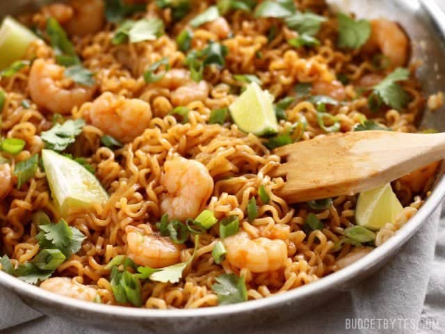 These spicy Lime Shrimp Dragon Noodles are a fast, easy, and inexpensive alternative to take out. This version features tender shrimp and fresh lime. BudgetBytes.com Close up of Lime Shrimp Dragon Noodles in the skillet with a wooden pasta fork