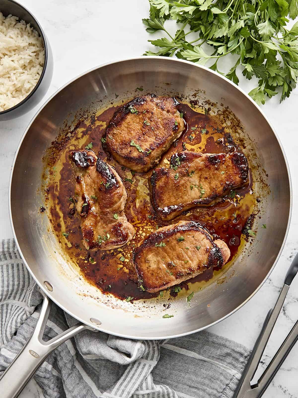 These juicy Glazed Pork Chops are sweet, salty, and a little spicy. The sugar glaze helps keep the chops moist and tender! Budgetbytes.com Overhead view of glazed pork chops in a skillet.