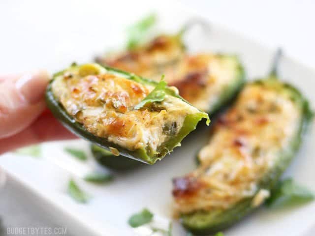 Cheesy Scallion Stuffed Jalapeños are a quick, easy, and impressive appetizer for your game day get together or any party platter! BudgetBytes.com Close up of a cheesy stuffed jalapeño with a bite taken out.