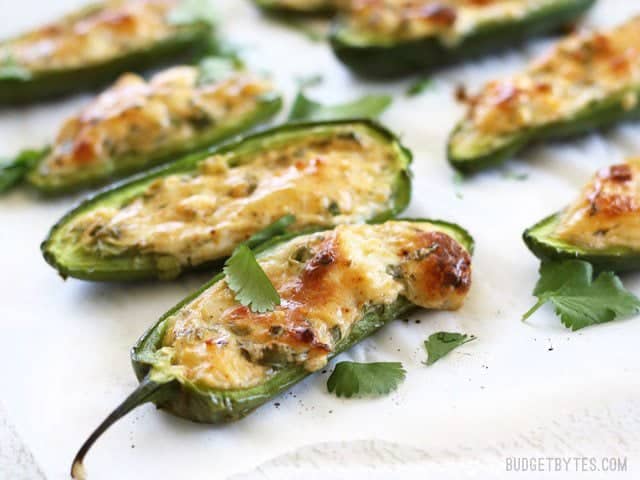 Cheesy Scallion Stuffed Jalapeños are a quick, easy, and impressive appetizer for your game day get together or any party platter! BudgetBytes.com Side view of baked cheesy scallion stuffed jalapenños, close up.