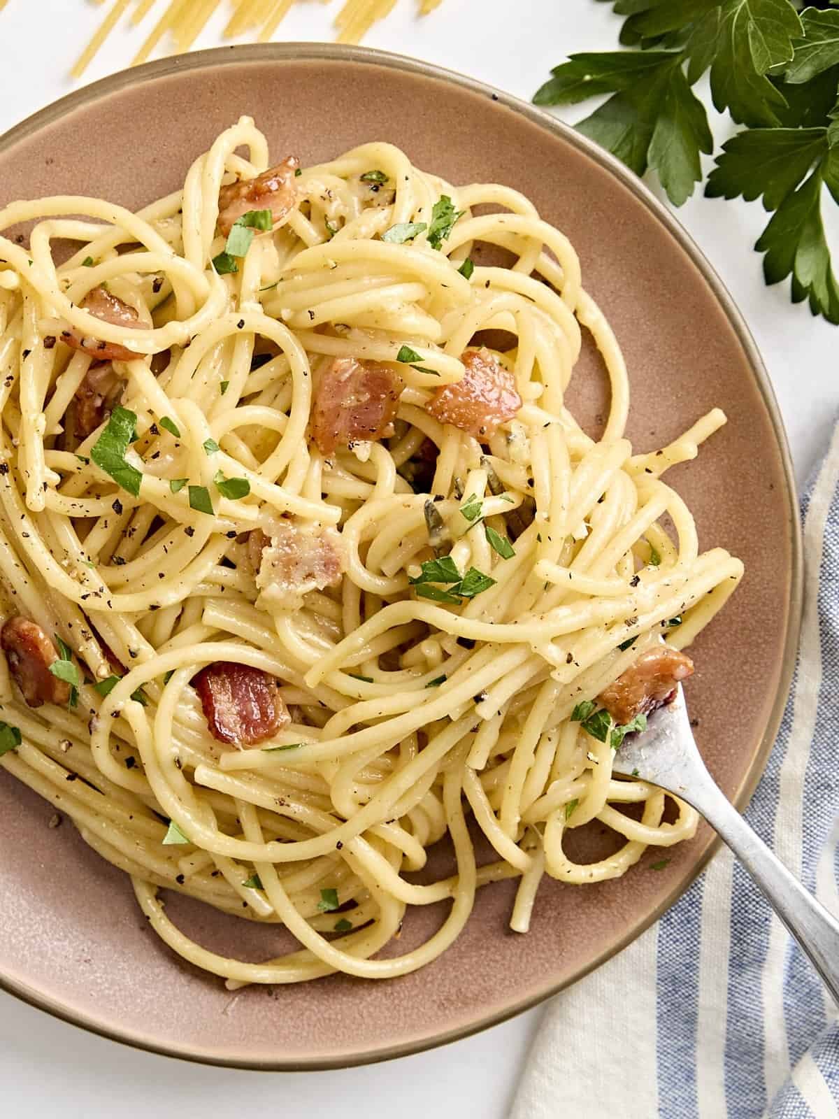 Overhead view of a plate of spaghetti carbonara with a fork.