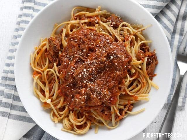 Top view of a plate of Sunday Slow Cooker Beef Ragù sitting on a gray and white napkin with a fork on the side