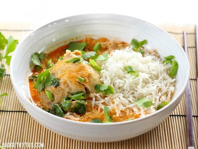 Thai Coconut Curry Chicken Thighs are easy to prepare but still have a bold flavor from Thai red curry paste, and a rich, comforting coconut curry broth. BudgetBytes.com Front view of a bowl full of Thai Coconut Curry Chicken Thighs with jasmine rice and cilantro