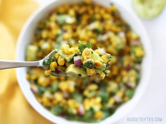 Warm Corn and Avocado Salad makes the perfect light and fresh side dish for enchiladas, grilled meats, tacos, or any summer meal. BudgetBytes.com Close up of a forkful of Warm Corn and Avocado Salad