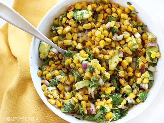 Warm Corn and Avocado Salad makes the perfect light and fresh side dish for enchiladas, grilled meats, tacos, or any summer meal. BudgetBytes.com Overhead view of Warm Corn and Avocado Salad with a fork stuck in the side of the bowl