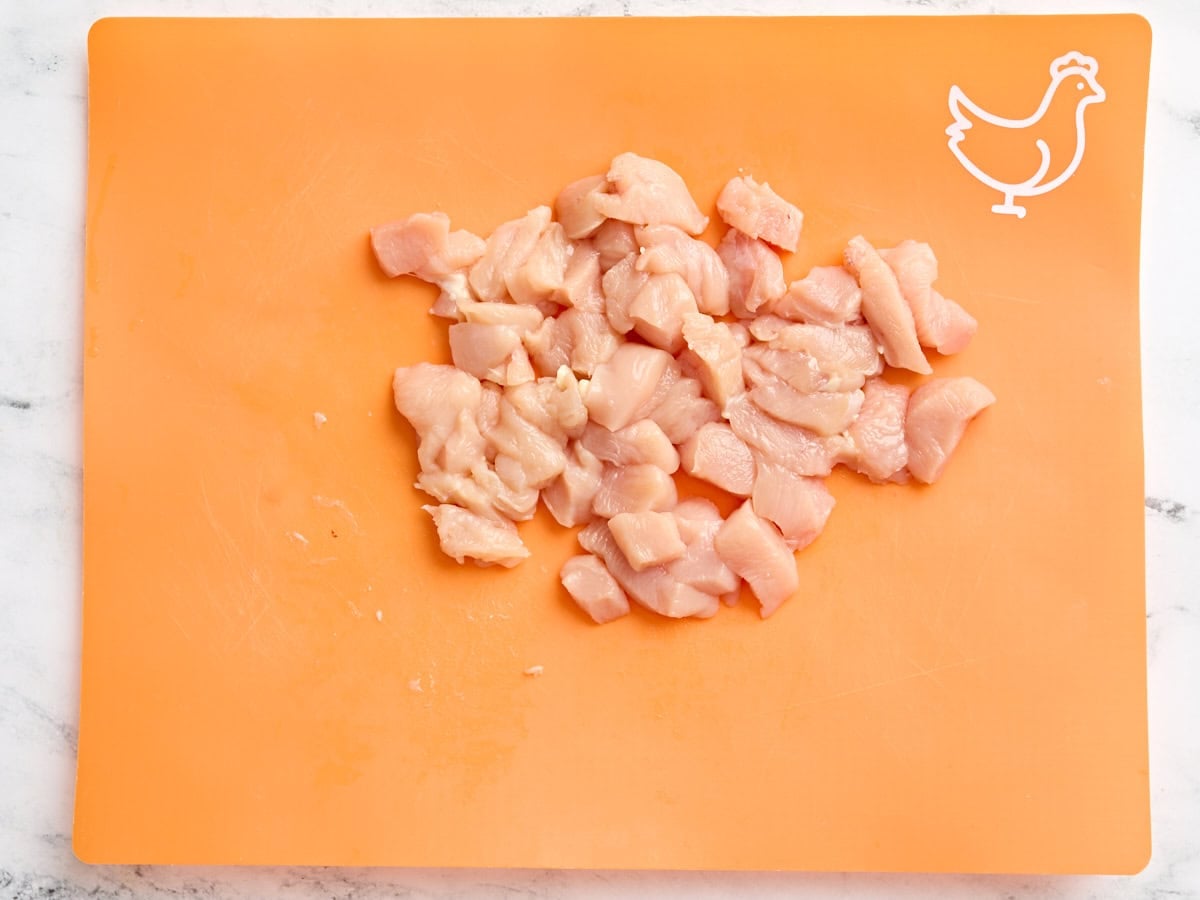 Diced chicken breast on a meat preparation mat.